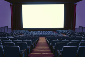 紫の通路を挟んで青い座席が配列された映画館のイラスト。スクリーンは壁一面に広がり、周囲の壁は薄紫で、床には紫と金色のパターンのカーペットが敷かれている。