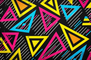 黒い背景にカラフルな三角形が配置された幾何学模様。ピンク、黄色、青の三角形がランダムに配置され、ストライプがアクセントになっている